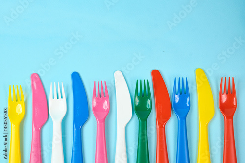 Multicolored plastic dishes on a blue background. The concept of environmental pollution by plastic, ecolog place for text, flat lay