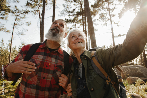Active happy senior couple hiking together in forest and exloring nature