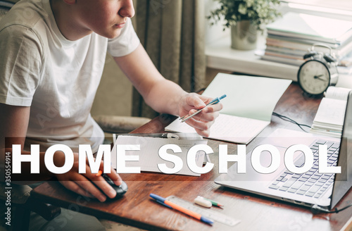 Concept of home school, online education and teleeducation. A teenager boy does his homework at a laptop because schools are closed due to the coronavirus pandemic. photo