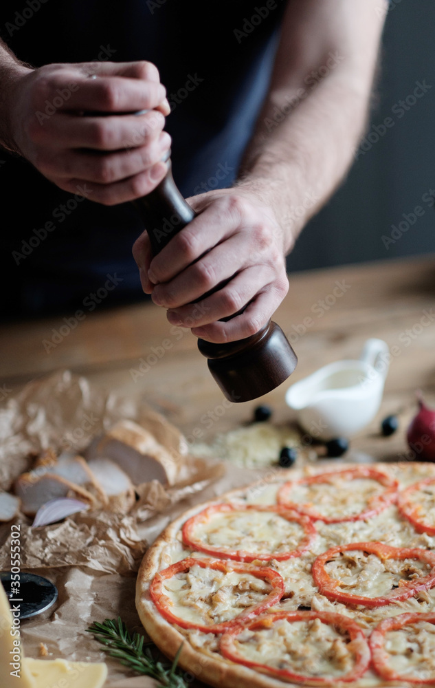 male hands are cooking pizza with sausage and ingredient on the wooden table in rustik style