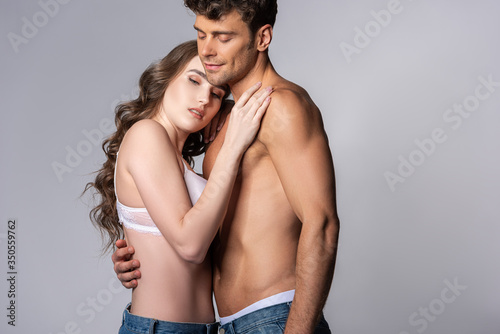 attractive girl and muscular man hugging isolated on grey
