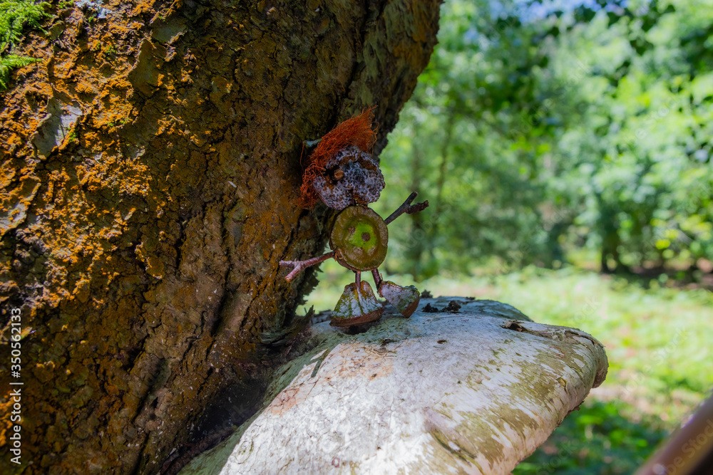 Handmade doll on a fungus that is attached to a tree trunk