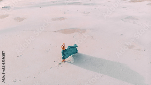 Woman wrapped in blue tissue posing in the desert.