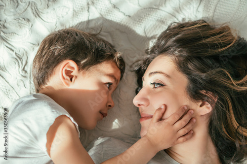 top view of cute toddler boy touching face of attractive mother