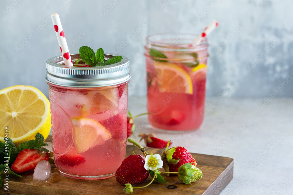 Summer drink refreshing. Lemonade with fresh strawberries, ice and lemons on a light stone countertop. Copy space. Summer drink refreshing. Lemonade with fresh strawberries, ice and lemons on a light stone countertop. Copy space.