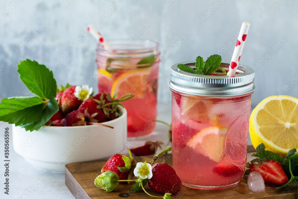 Summer drink refreshing. Lemonade with fresh strawberries, ice and lemons on a light stone countertop. Summer drink refreshing. Lemonade with fresh strawberries, ice and lemons on a light stone countertop.