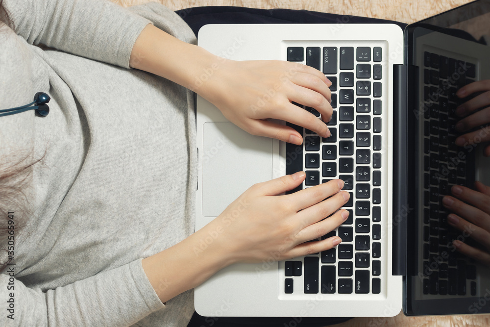 Fototapeta premium Girl working on a laptop at home on the couch. Freelance and Remote Quarantine Concept, top view