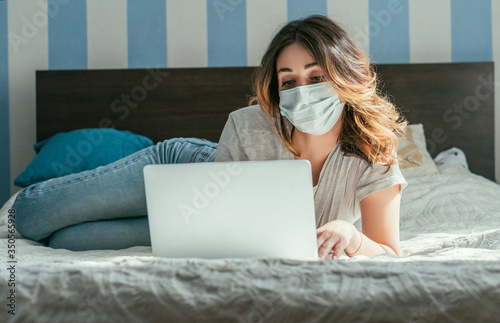 selective focus of freelancer in medical mask using laptop in bedroom