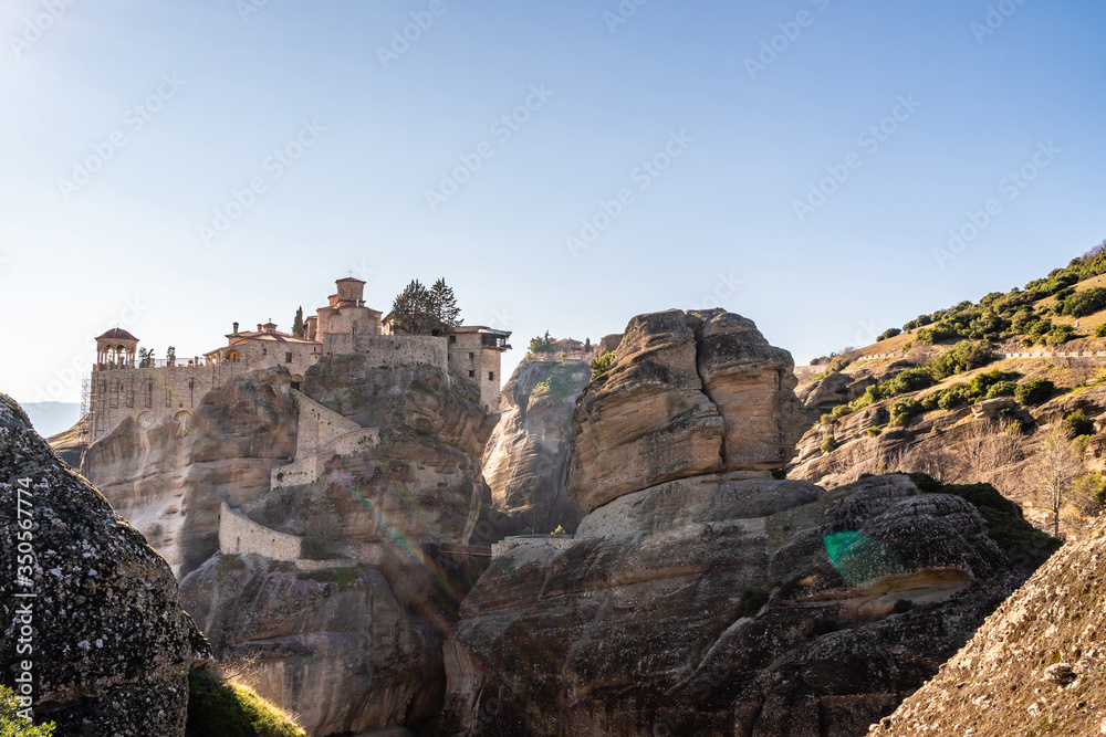 Sunlight on orthodox monastery on rock formations against blue sky in meteora