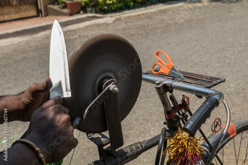 sharpening a glossy kitchen knife on water stone in India photo