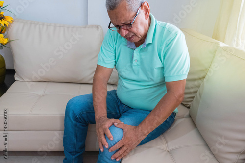 old age, health problem. Older man suffering from leg pain at home