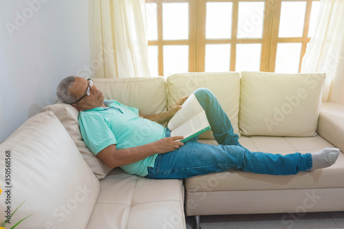 Older man sleeping on his couch at home. Sick grandpa resting in the living room. Health care / Health care concept.