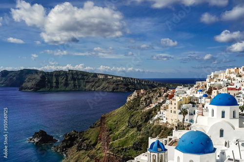 blue-domed churches near white houses and tranquil sea in santorini