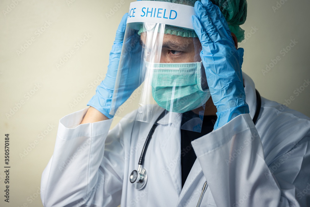 Closeup Asian male doctor wearing face shield and Personal Protective  Equipment, PPE suit with stethoscope prepare check up coronavirus patients.  Stock Photo | Adobe Stock