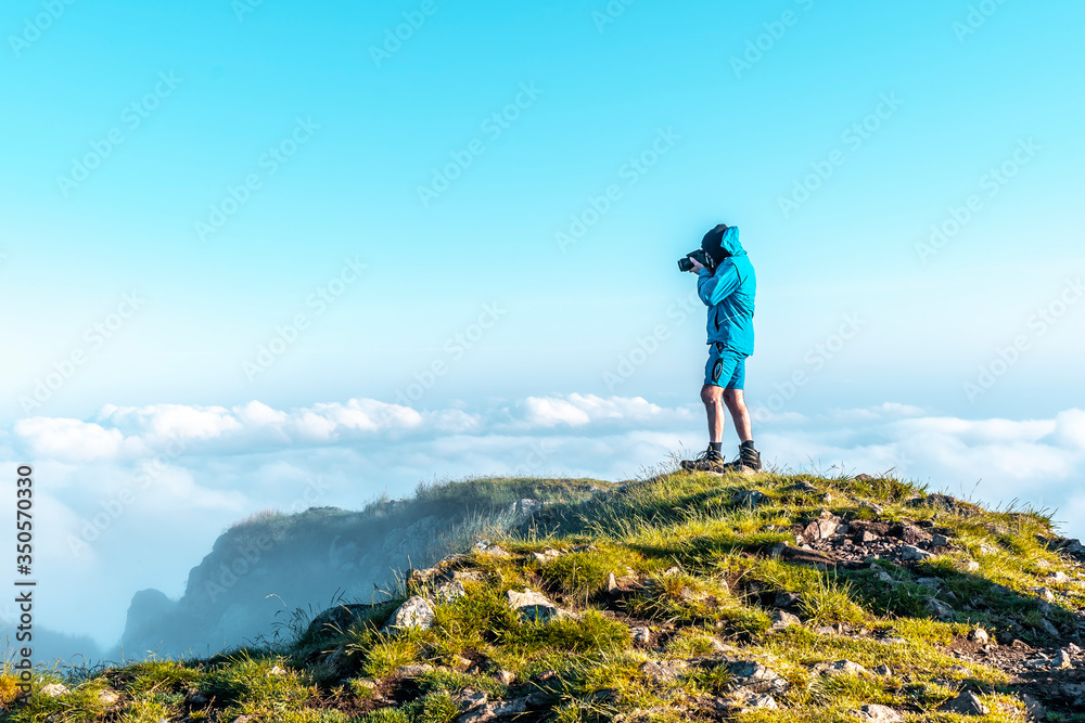 A photographer in the foggy weather at sunrise of the Peñas de Aya mountain or also called Aiako Harria, Oiartzun. Gipuzkoa Province of the Basque Country. Vertical photo