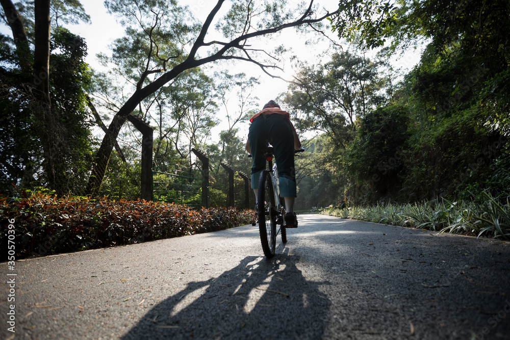Woman cycling on bike path at park on sunny day Woman cycling on bike path at park on sunny day