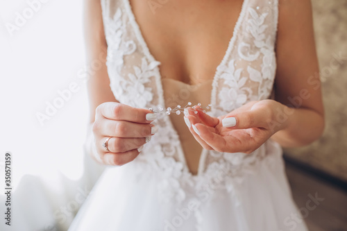 The bride wears a wedding dress, tries on earrings. The bride's morning training camp. women's accessories on wedding day.