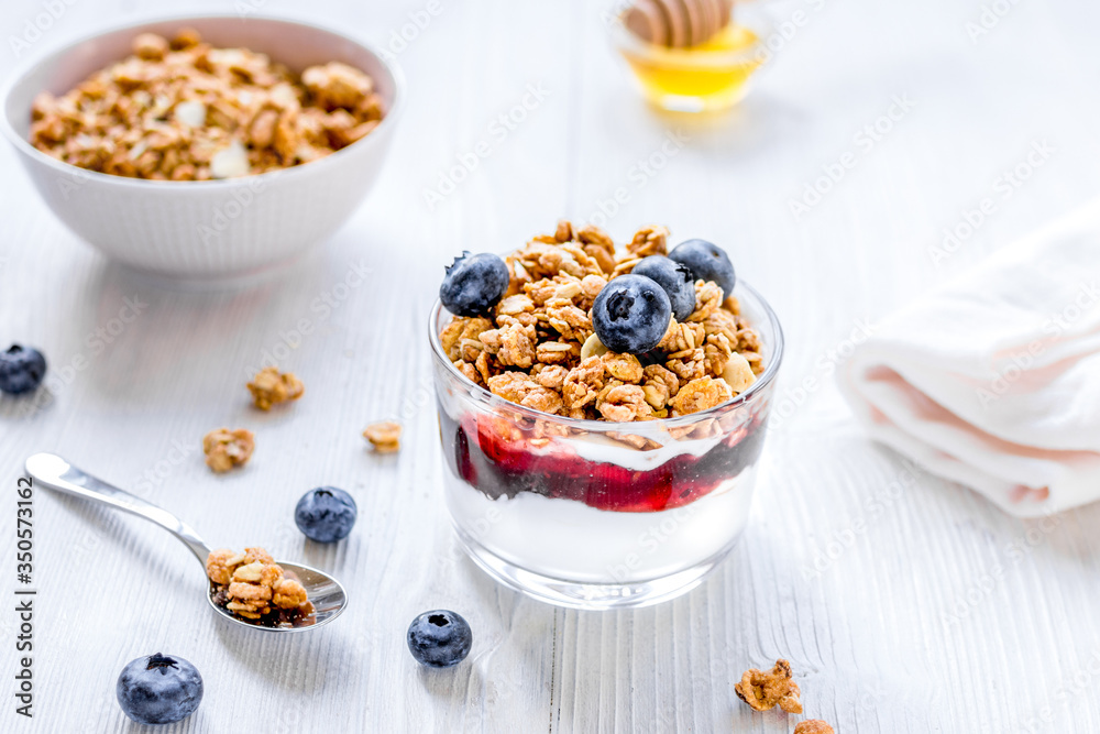 Fitness breakfast with muesli, honey and berries on white table Fitness breakfast with muesli, honey and berries on white table