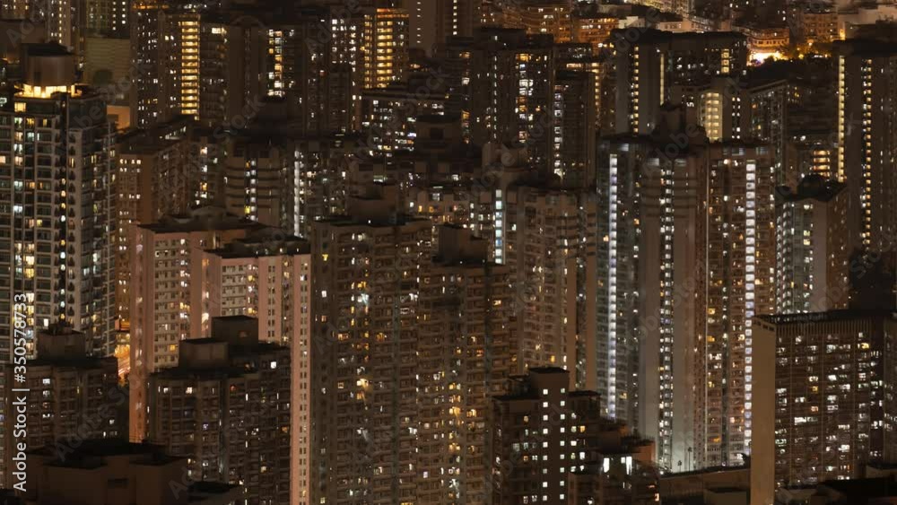 Crowded city with lights turning on and off at night. Hong Kong city apartments buildings at night. Zoom in.