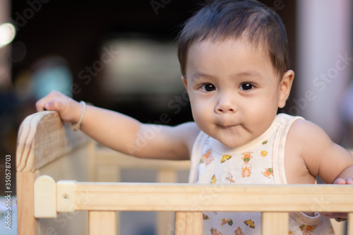 Portrait of baby toddler in baby walker. Expressive child plays toys.