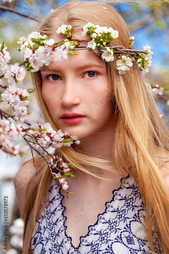 Portrait of a young blonde girl posing in spring park