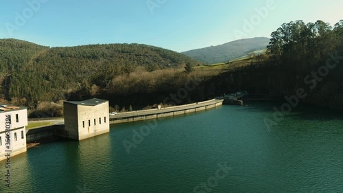 Aerial view of a very slowly movement to the right over a reservoir near a dam in front and a car behind