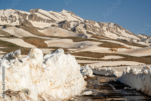 Lake Egrigol (eğrigöl), a hidden gem sitting at 2,350 meters in the foothills of Geyik Mountain in Antalya province, Surrounded by 3 or 4 meters of snow on one side and mountain wild flowers photo