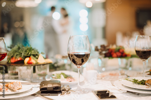 Banquet. Cover the table with a white tablecloth. On the table are glasses of wine, dishes with food. Against bokeh