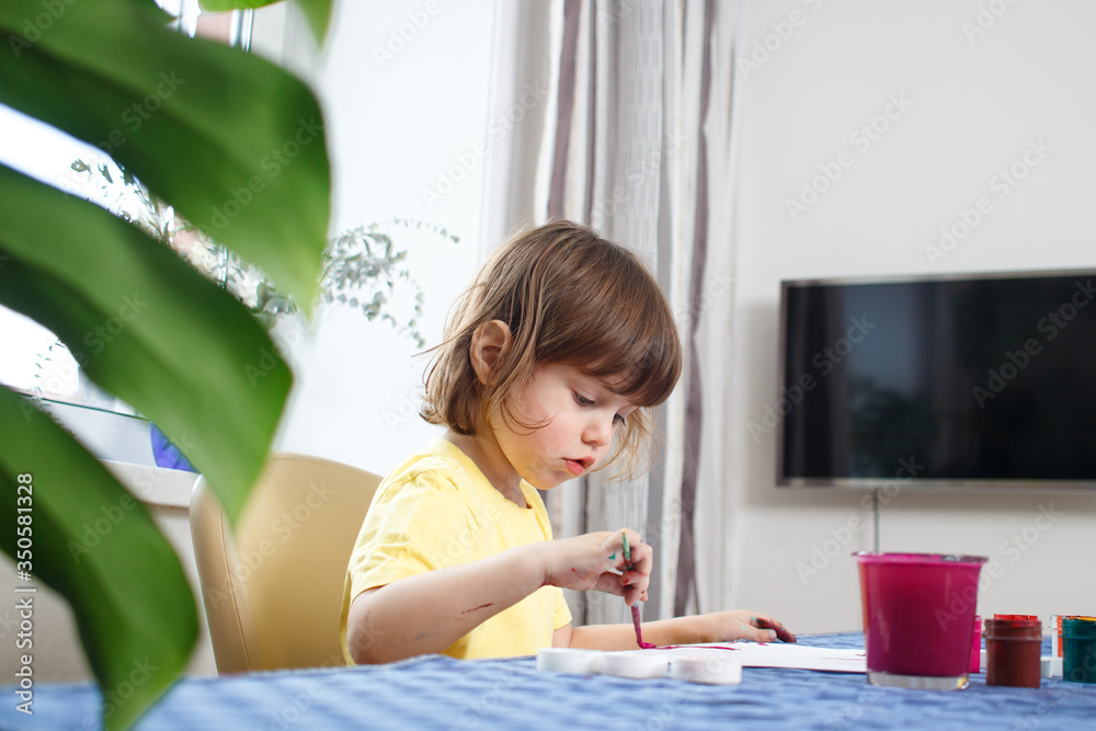 Little caucasian girl draw picture gouache in home interior during coronavirus self-isolation and quarantine. Creativity concept. Cute three year old baby is engaged in creativity. Little caucasian girl draw picture gouache in home interior during coronavirus self-isolation and quarantine. Creativity concept. Cute three year old baby is engaged in creativity.