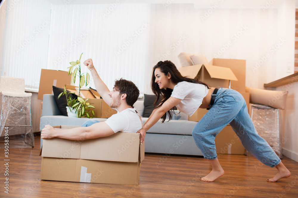 Happy couple is having fun with cardboard boxes in new house at moving day Happy couple is having fun with cardboard boxes in new house at moving day