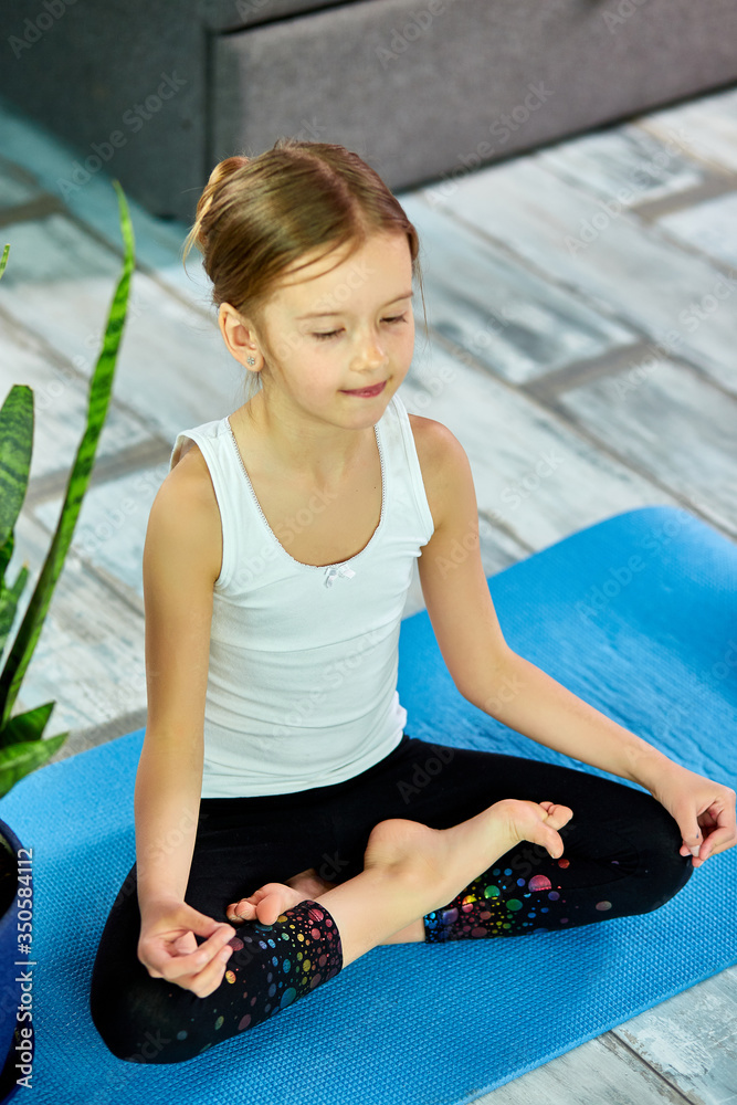 A girl sitting in yoga asana on a blue background.