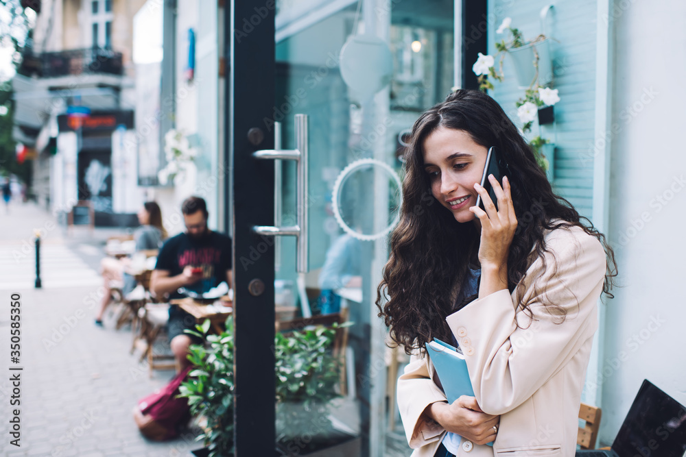 Fototapeta premium Cheerful woman speaking on phone in street