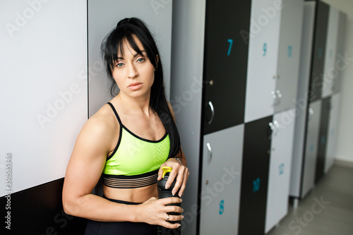 Girl drinking water in locker room after fitness training. Active lifestyle