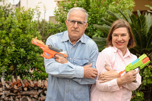 coppia di anziani in giardino gioca con delle pistole ad acqua photo