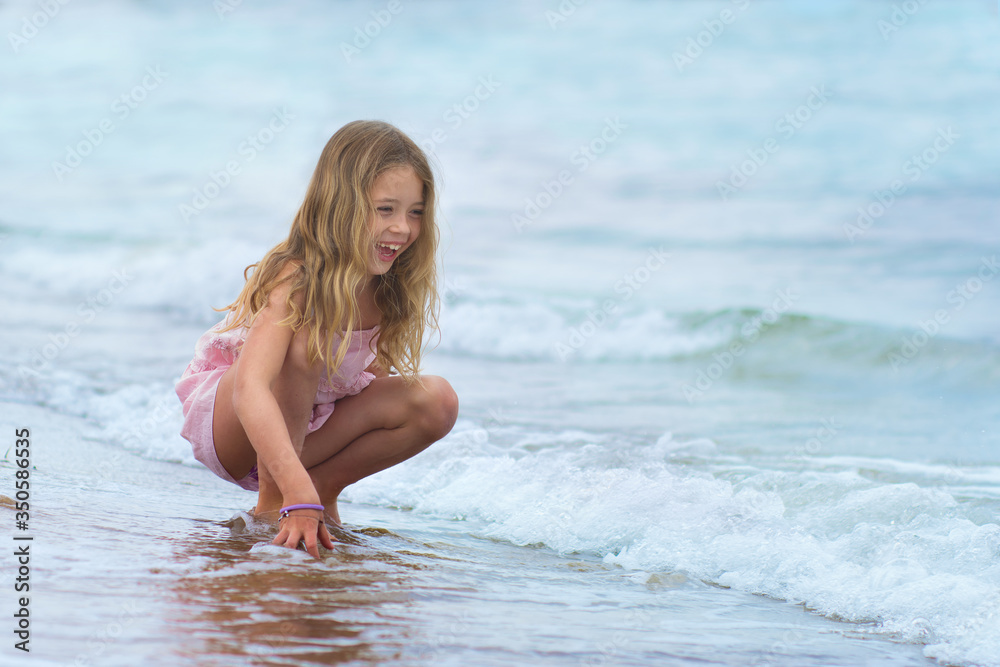 young girl is playing at the seaside in Italy, the wave splash girl and girl is smiling, holiday concept young girl is playing at the seaside in Italy, the wave splash girl and girl is smiling, holiday concept