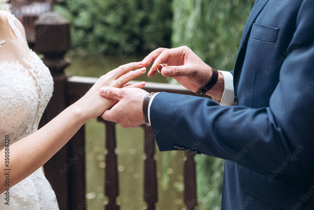 The bride and groom wear wedding rings. A young couple at a wedding ceremony. hands closeup. The bride and groom wear wedding rings. A young couple at a wedding ceremony. hands closeup.