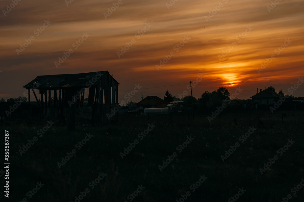 Silhouette of a wooden building in the late evening during the red sunset in the village | KOROVYAKOVA, SVERDLOVSKAYA OBLAST - 9 MAY 2020.