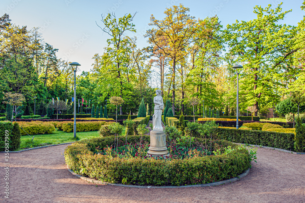 gypsum sculpture of a woman with a jug on a flowerbed among bushes and trees in a city park in Bucha, Ukraine