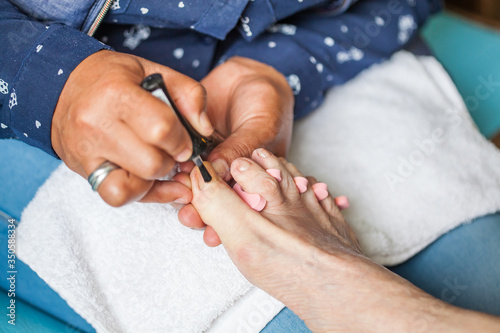 Close up of a senior woman foot while getting a pedicure at home during Covid-19 pandemic