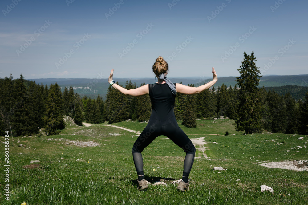 The girl does exercises from yoga on the background of a mountain landscape.