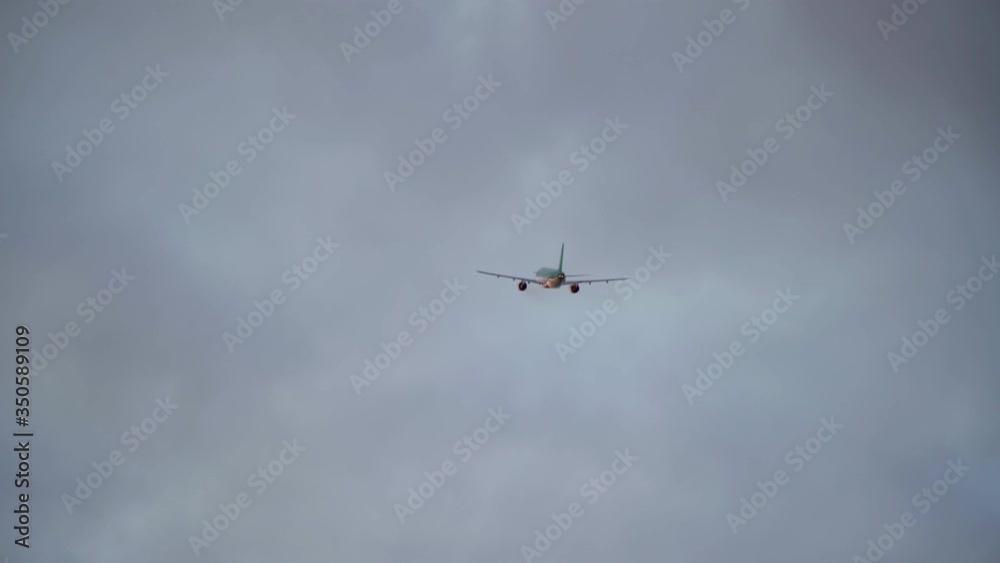 A passenger airliner takes off, in clouds at sunset.