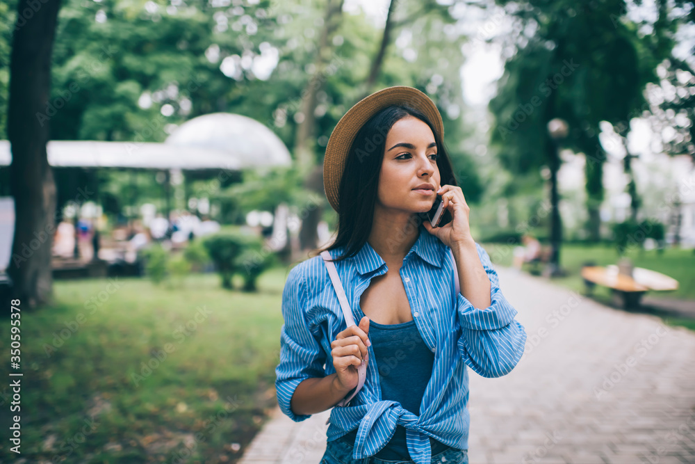 Charming female in stylish hat contacting people via cellphone gadget connected to roaming outdoors, millennial Caucasian woman looking phoning for discussing park walking using 4g wireless Charming female in stylish hat contacting people via cellphone gadget connected to roaming outdoors, millennial Caucasian woman looking phoning for discussing park walking using 4g wireless