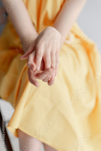 A young girl s thin hands. Girl in a yellow dress 