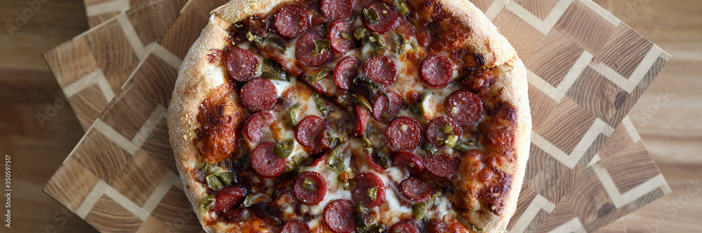 Delicious pizza with sausages lies wooden surface Delicious pizza with sausages lies wooden surface