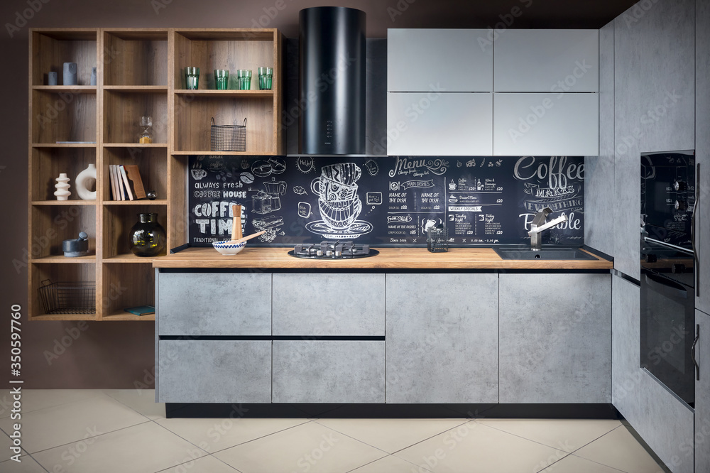 © R_Yosha - Massive cottage urban rustic loft style contemporary kitchen interior in wooden brushed oak table top gas hob fan and gray stoneware facade and granite sink with chalk lettering background.