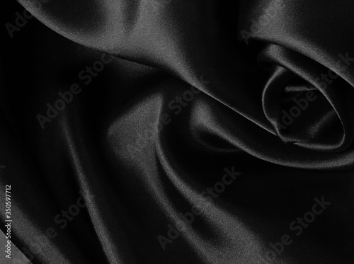 Shiny black crumpled fabric background. Liquid wavy shape. photo