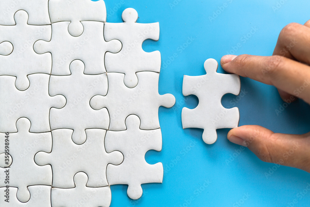 Two women are trying to connect a pair of puzzle pieces. Symbol of association and connection. Concept of business strategy. Two women are trying to connect a pair of puzzle pieces. Symbol of association and connection. Concept of business strategy.