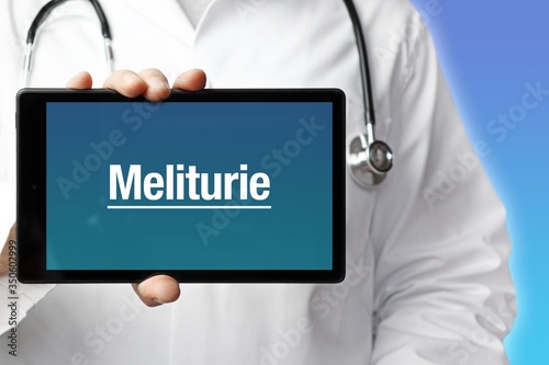 Meliturie. Arzt mit Stethoskop hält Tablet-Computer in Hand. Text im Display. Blauer Hintergrund. Krankheit, Gesundheit, Medizin photo