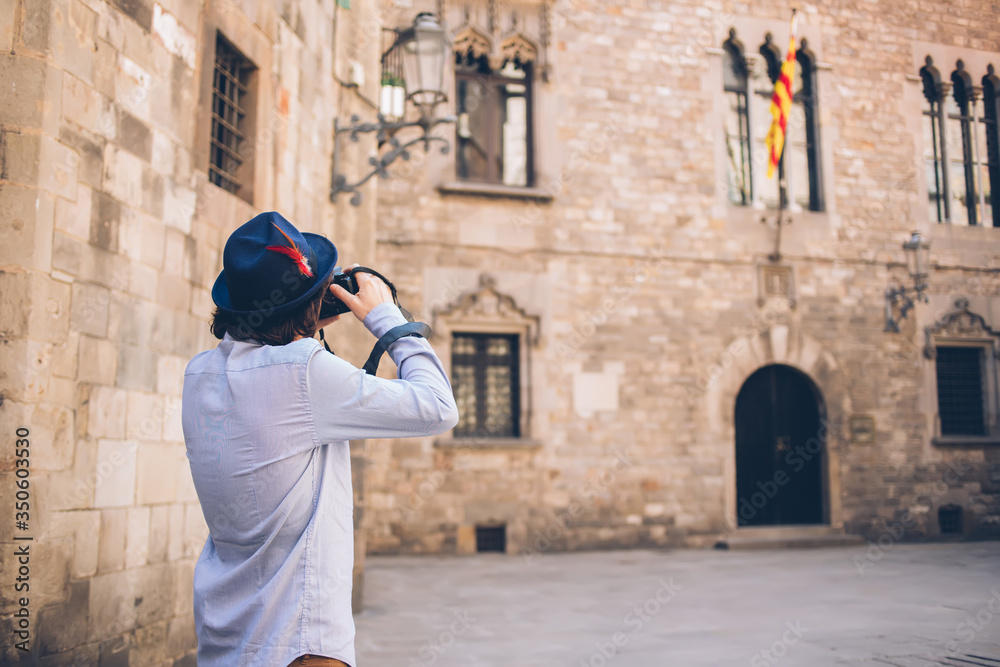 Traveler taking photo of medieval building with digital camera in old town