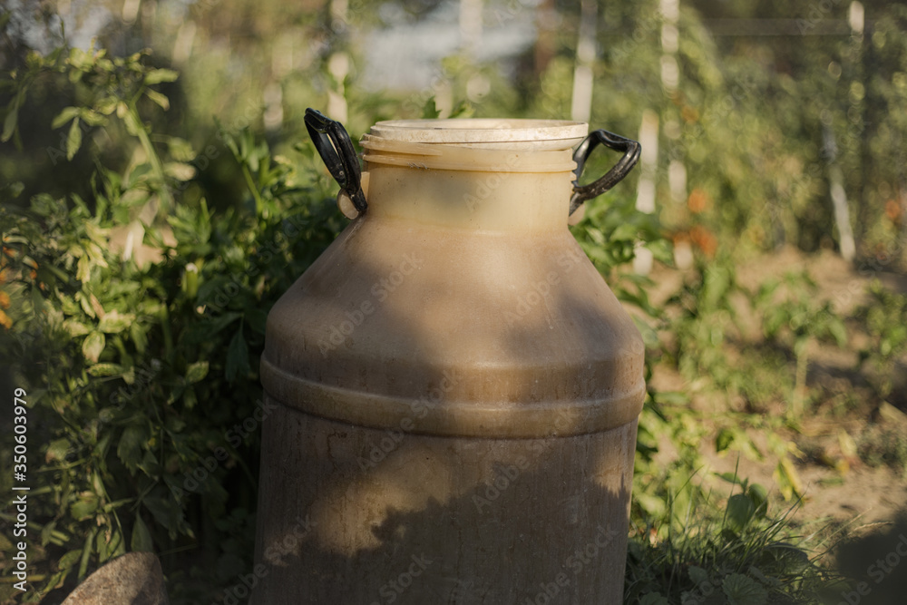 Close up of plastic container for liquid in the garden. Old dirty water barrel Close up of plastic container for liquid in the garden. Old dirty water barrel